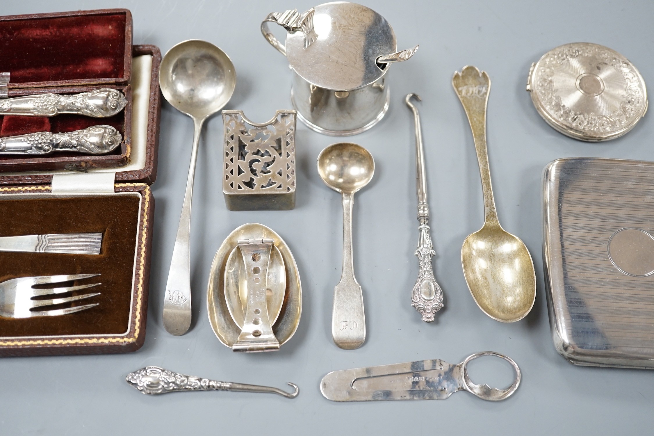 A small collection of sundry silver items including flatware, compact, cigarette case, mustard pot, sterling folding spoon, match sleeve, book mark, cased spoon and fork and a cased Victorian spoon and fork.